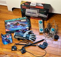 Full view of Power Glove in box, glove with cables, sensor bars, manual, paddle controllers, power adapters, and SNES box