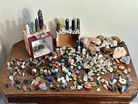 Wide view of entire lot on wooden table showing all stones, clusters, pendulums and bead case