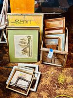 Photo showing a collection of large vintage framed prints and a large printed board labeled 'Marcon Zenit', as well as a wooden crate with smaller framed prints inside, placed on a carpet.