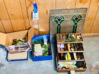 Photo showing the stained glass window panel with decorative green and brown elements alongside three boxes containing assorted stained glass pieces in various shapes and colors.