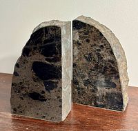 Photo showing two black marble bookends positioned side by side, displaying both the polished and rough natural edges.