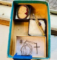 Overview of all three items (cameo brooch, bar brooch, cross necklace) arranged in box