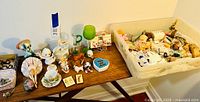 Photo shows all vintage little girls decorative items including figurines and toys arranged on table in two bins.