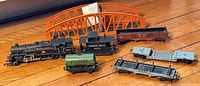 Wide shot showing the entire set with bridge, loco, tender, tanker, multiple freight cars arranged on wooden floor