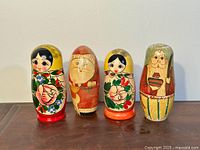 Four vintage Russian matryoshka dolls in a row on wooden surface, showing different painted characters.