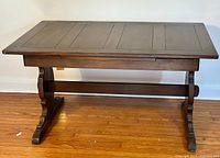Front view of the Ercol draw leaf dining table showing full rectangular top and trestle base on a hardwood floor.