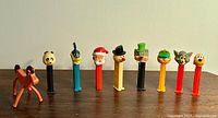 Front view of nine vintage PEZ candy dispensers with various character heads, showing colors and designs.