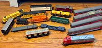Collection of 17 HO scale Tri-ang locomotives and railroad cars arranged on wooden floor.