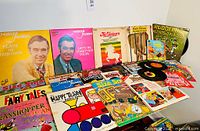 Wide view of multiple vintage children's vinyl LP records displayed including Mister Rogers albums, fairy tales, and classic story themes.