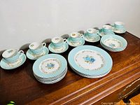 Full view showing 6 tea cups on matching saucers, 6 small plates, and 6 large plates arranged on wooden surface