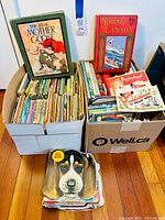 Photo showing two large boxes filled with many assorted vintage children's books including two prominent books The Real Mother Goose and Young Canada, and a pile of board books with a dog image on top.