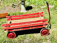 Side view of the red wooden wagon with Jetliner branding on side panel and red metal wheels, showing pull handle and removable side panels.