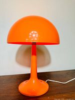 Front view of orange mushroom lamp on wooden surface against white background