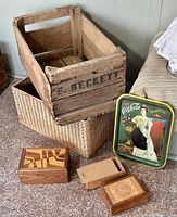 Wood containers including wooden crate, wicker basket, three small wooden boxes, and vintage Coca-Cola metal tray arranged on floor.