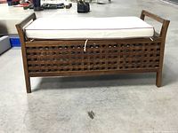 Front view of wooden bench with lattice sides and attached cushion on top.