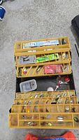 Four yellow tackle boxes with assorted fishing lures and tackle arranged on the floor