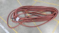 Photo of a coiled heavy duty hose on a concrete floor with yellow lines.
