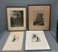 Full view of the four art prints, two framed and two unframed, varying in size and style featuring architectural and natural scenes and boats.