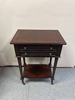 Front view of the Bombay nightstand showing the single drawer, legs, and lower shelf with casters.