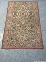 Full view of rectangular continental hook rug with floral and leaf motifs and a rust-colored border.