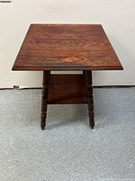 Front view of the wooden square end table with visible turned legs and lower shelf, showing the dark wood grain and surface.