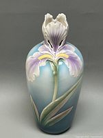 Front view showing the detailed iris flower relief and gradient blue color on vase body.