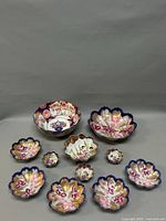 Full view of all 12 bowls and dishes showing various sizes and decorative patterns including blue, gold, pink, purple, and traditional Kutani figures.