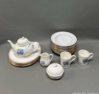 Overview of Royal Doulton Christopher Stuart tea set with teapot, creamer, sugar bowl, mugs, stacked dinner and soup plates