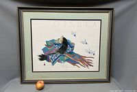 Framed lithograph showing a traditional Japanese figure in colorful robes with birds flying beside, signed by Otsuka.