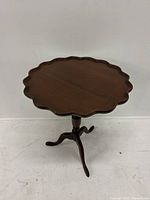 Front and full view of the round scalloped top wood pedestal end table against white background.