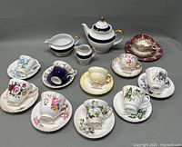 Full set of porcelain teapot, creamer, sugar bowl, 10 cups and 10 saucers arranged on grey surface