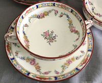Close-up of a single Minton bowl resting inside its matching saucer showing intricate floral and geometric hand-painted design with gold accents.
