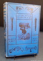 Front cover of antique blue hardcover book with embossed magic-related imagery and gold text on spine.