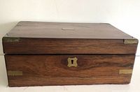 Closed view of the rectangular mahogany writing slope with brass corner mounts and central lock plate on front