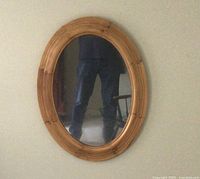 Full view of oval pine frame mirror hanging on wall showing size and shape.