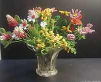 Full view of the bouquet of vintage beaded glass wild flowers in an antique pressed glass vase against a black background