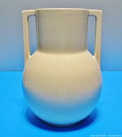 Front view of the large double-handled vase showing the rounded body and sand colored vitrified glaze.
