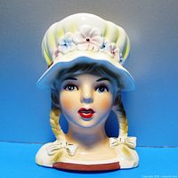 Front view of vintage Relpo ceramic head vase showing the girl's face with bonnet and braided hair.