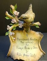 Front view of porcelain advertising sign with bird on apple blossom branch and inscription