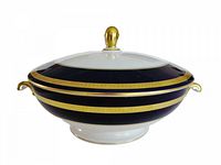 Side view of the covered vegetable bowl showing its cobalt blue body with gold bands and white base. Lid is on with gold finial and handles visible.