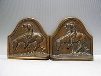 Front view of matching cast metal bookends showing relief scene of weary Native slumped on horse