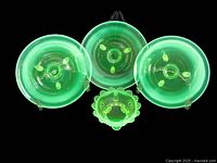 Overhead view of three plates and one bowl glowing green under black light