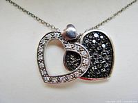 Close-up of overlapping open and closed hearts showing clear and black stones