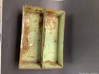 Top view of vintage metal garden tool carrier showing divided compartments, original green paint with chipping and rust