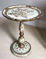 Side view of the vintage Italian Florentine cocktail table showing turned pedestal base and scalloped round top with decorative painting.