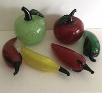 Full view showing two large glass apples, one green and one red, with stems and leaves, alongside four glass peppers in red and yellow with green stems.