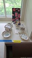 Top view of all items displayed near window including floral Aynsley trinket boxes and decorative dishes, with a floral greeting card in background.