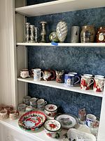 Full view of shelves displaying Christmas-themed mugs, candlesticks, bowls, plates, and other holiday dishware and decor items.