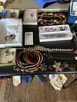 Overview of assorted jewelry including necklaces, bangles, brooches, and earrings on table