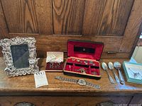View of all items lined up including picture frame, watch, spoons, pins, cufflinks sets.